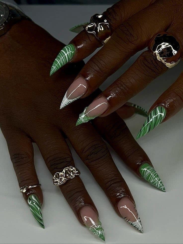 Long stiletto nails in green leaf prints with white line art and silver rings