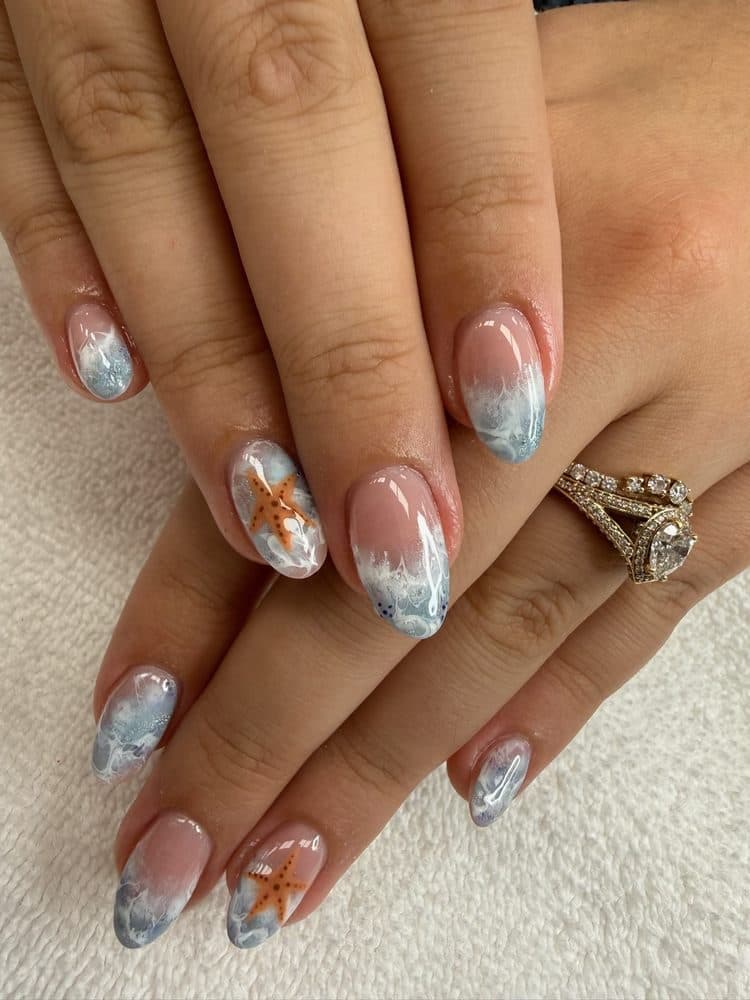 Almond gel nails with soft blue ocean-wave tips and orange starfish